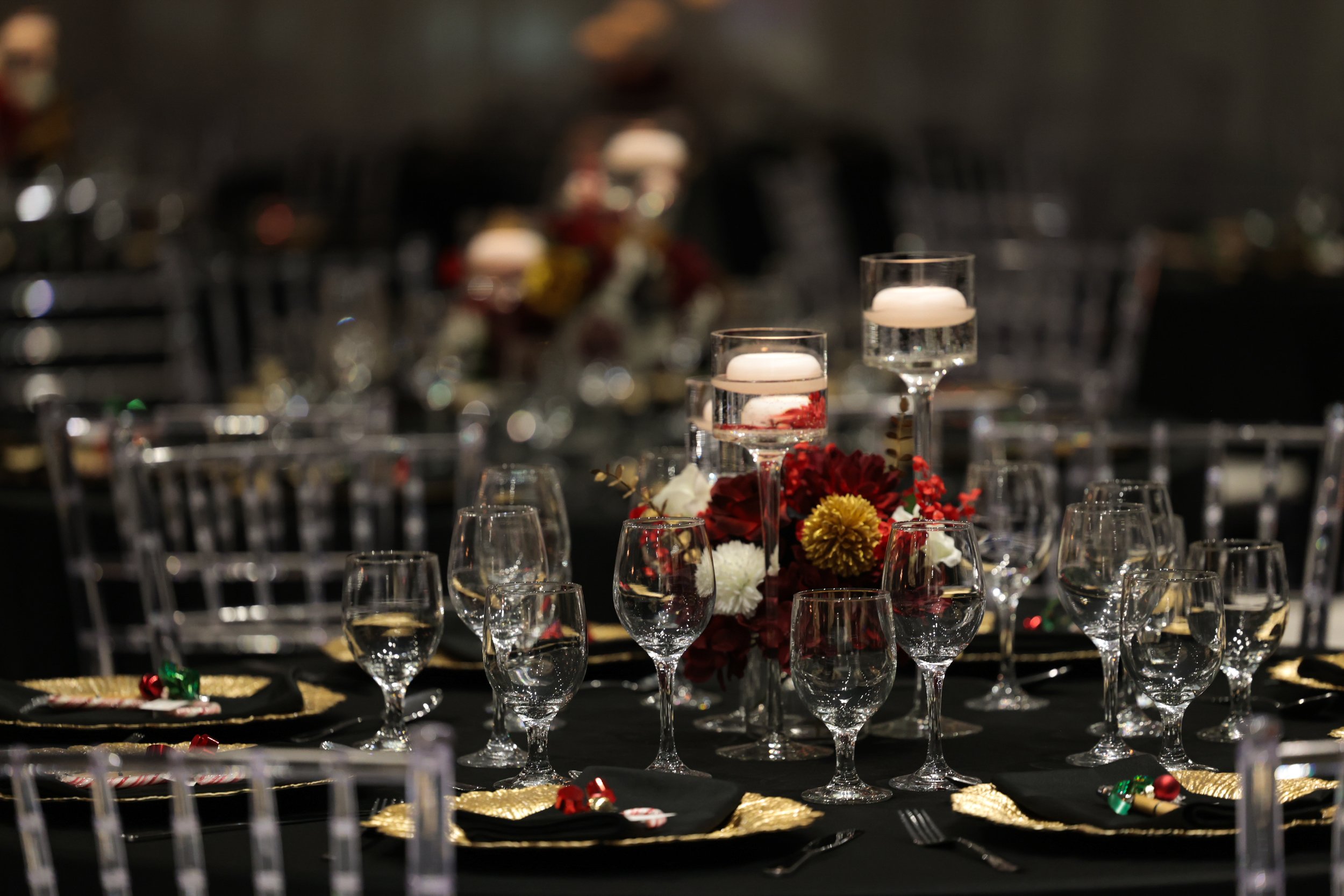 Elegant banquet table decorated with floral centerpiece and floating candles in water glasses, set for a formal event.