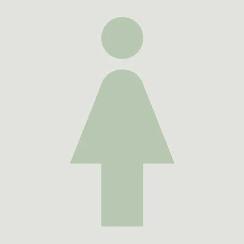 A minimalist, light green female restroom icon on a light gray background.