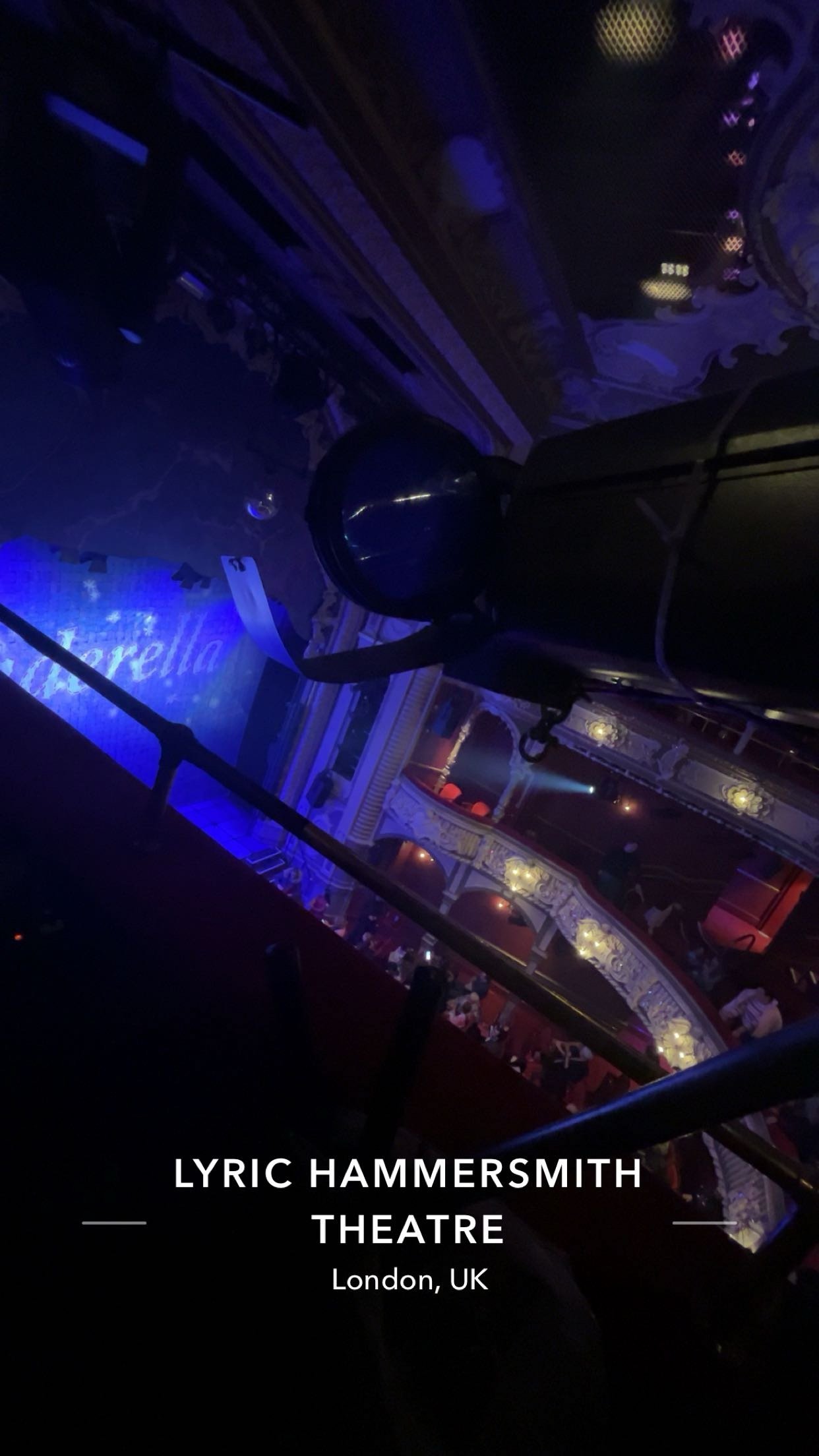 View of Lyric Hammersmith Theatre interior, showing a balcony, a stage with blue lighting, and ornate architectural details, taken from above on a balcony