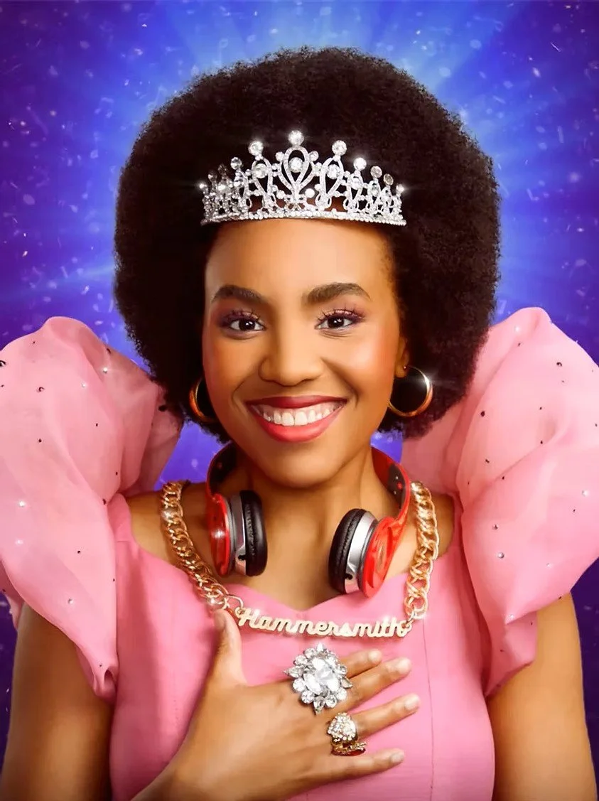 Woman with a large afro hairstyle wearing a silver tiara, pink dress with puffy sleeves, gold chain necklace reading 'Hammermith', large diamond ring, hoop earrings, and headphones around her neck, smiling against a purple background with sparkles.