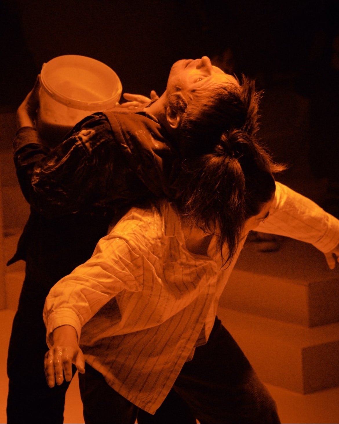 A person holding a bucket while another person leans back with arms outstretched.