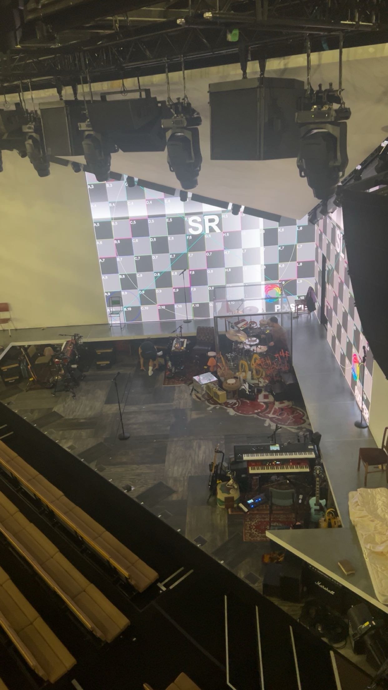 Stage setup with musical instruments and video screens in a theater or concert hall.