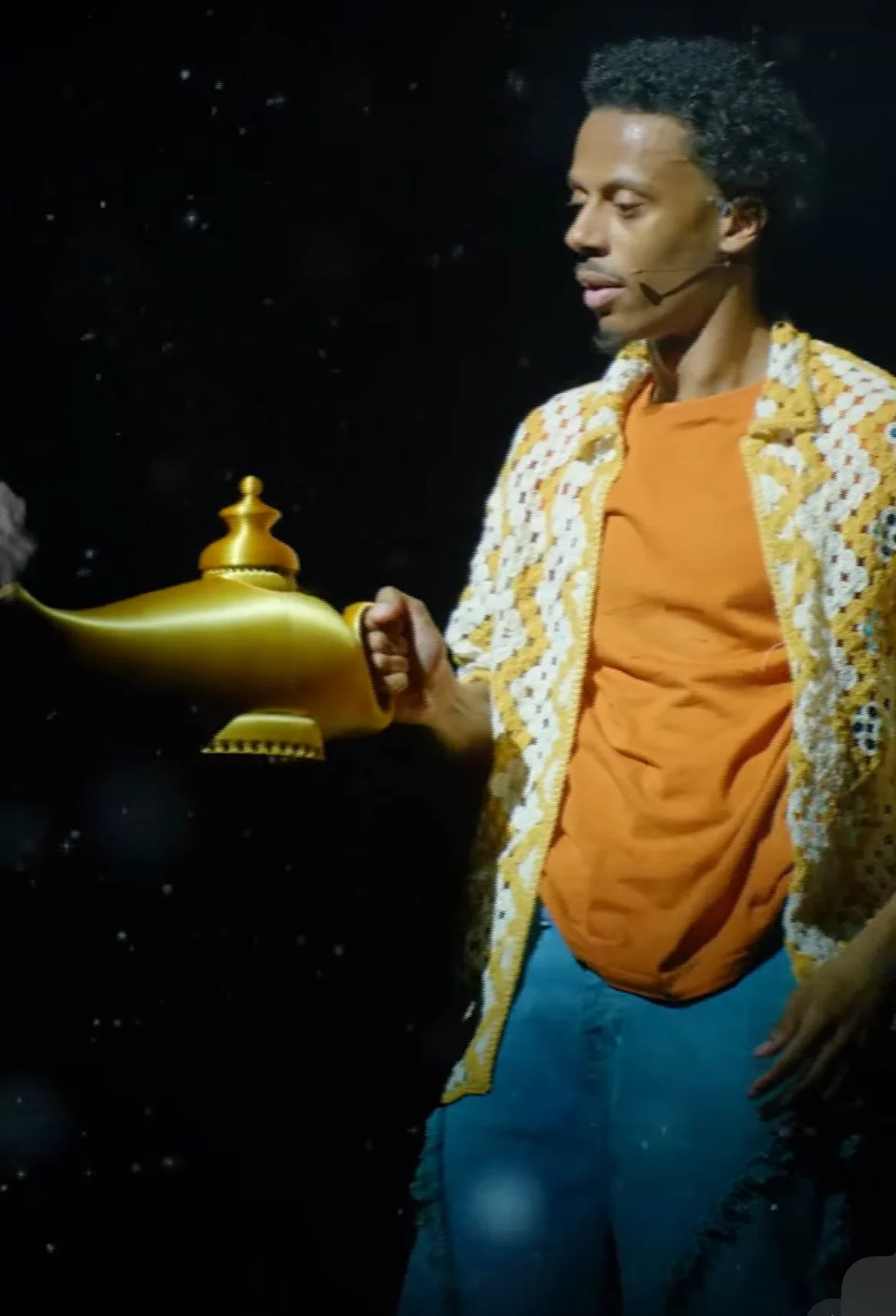 A man holding a golden lamp against a dark, starry background.