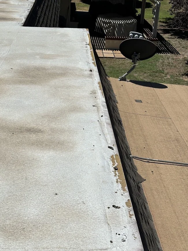 Deteriorated foam roof coating and exposed roof edge requiring repair.