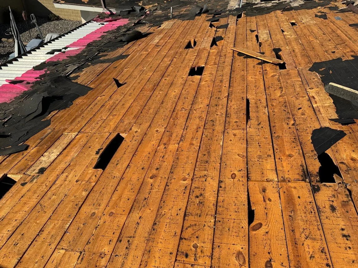Exposed wood roof deck with openings and deteriorated areas discovered during tear-off