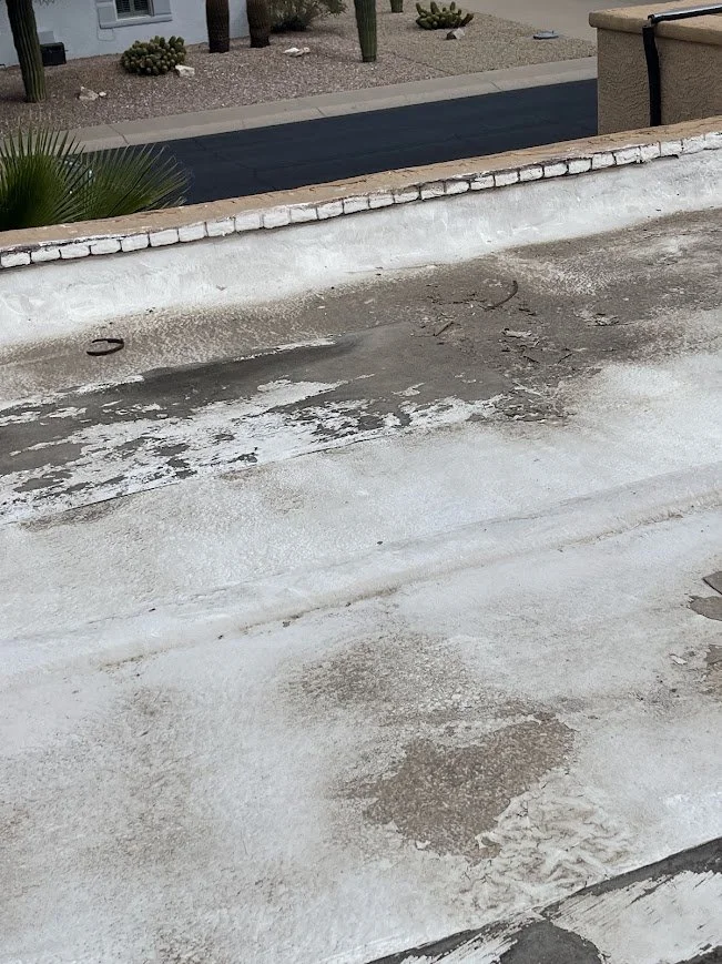 Deteriorated roof coating with exposed underlying roofing material on a low-slope roof.