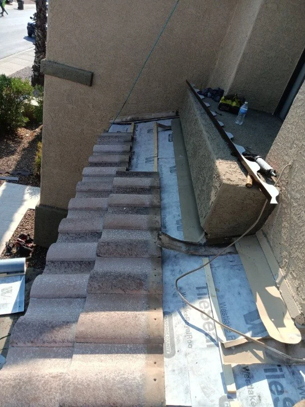 Tile roof flashing and underlayment work at a residential wall transition.
