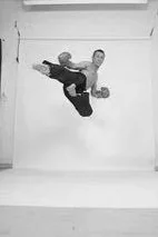 A person performing a high jump with a dynamic pose against a plain background.