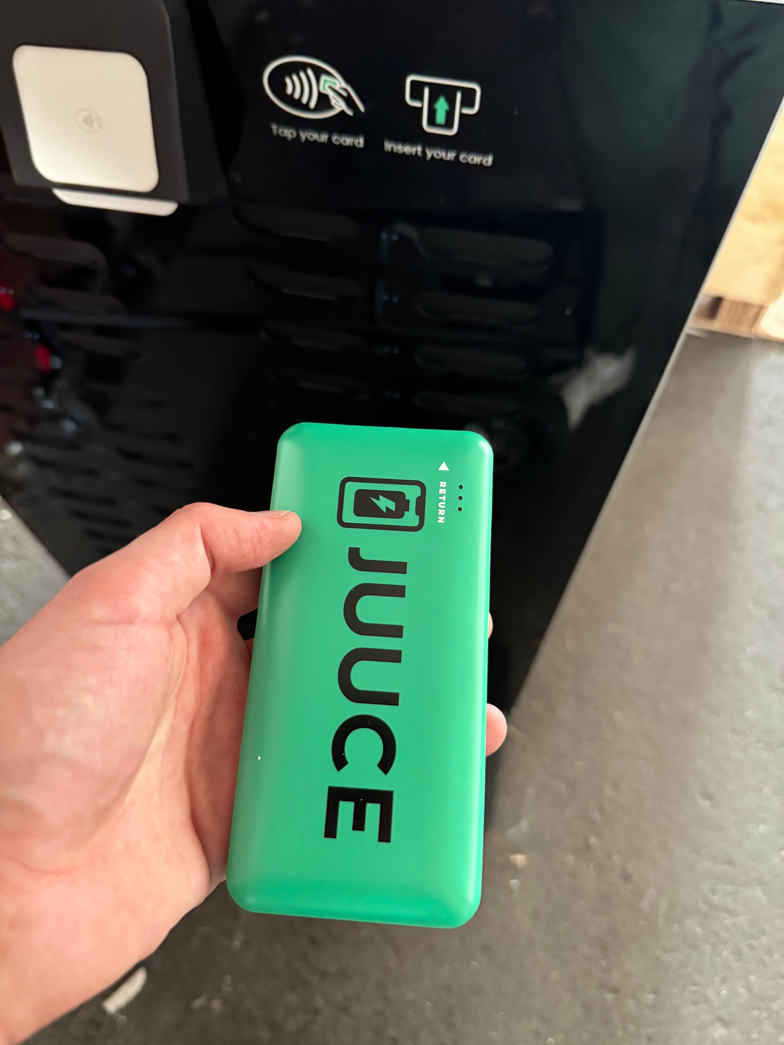 Person holding a green Juuce device near a vending machine that prompts to tap your card or insert your card.