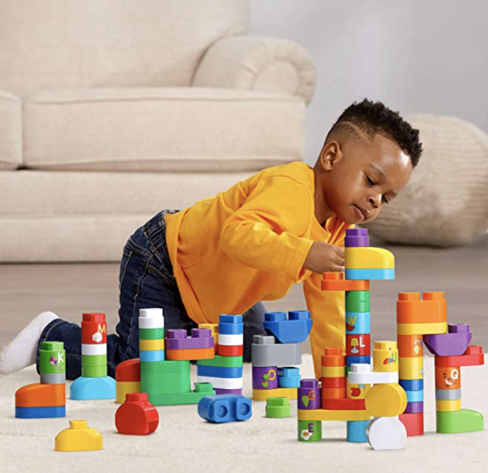 A young boy playing with colorful building blocks on the floor in a living room.