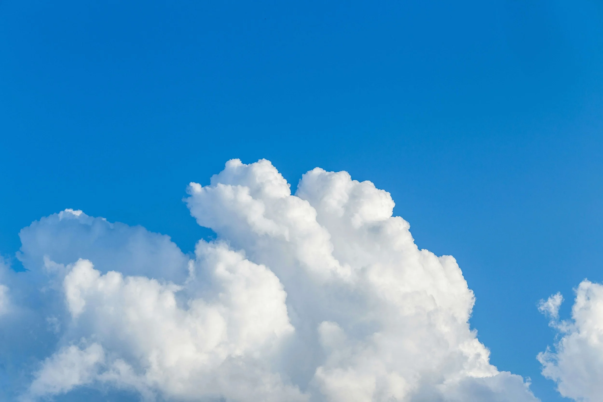 Bright blue sky with large white fluffy clouds.