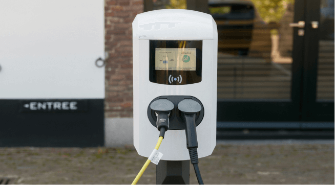 Electric vehicle charging station outdoors with two charging cables plugged in.
