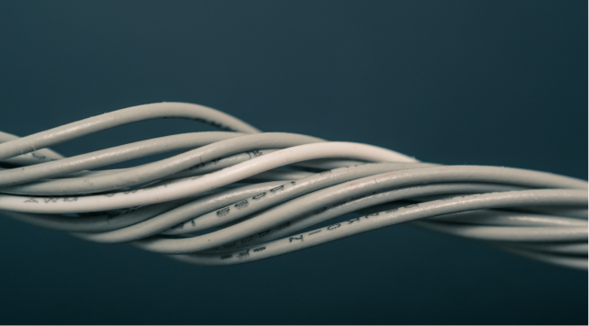 Close-up of twisted white electrical wires on a dark background.