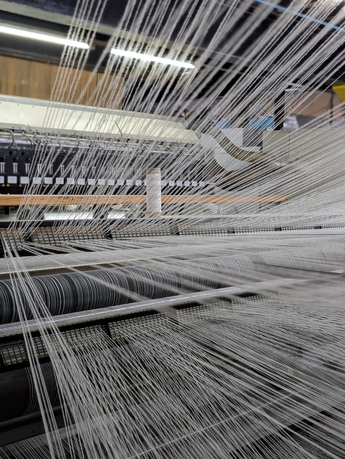 Close-up of fabric threads on a textile loom in a factory.