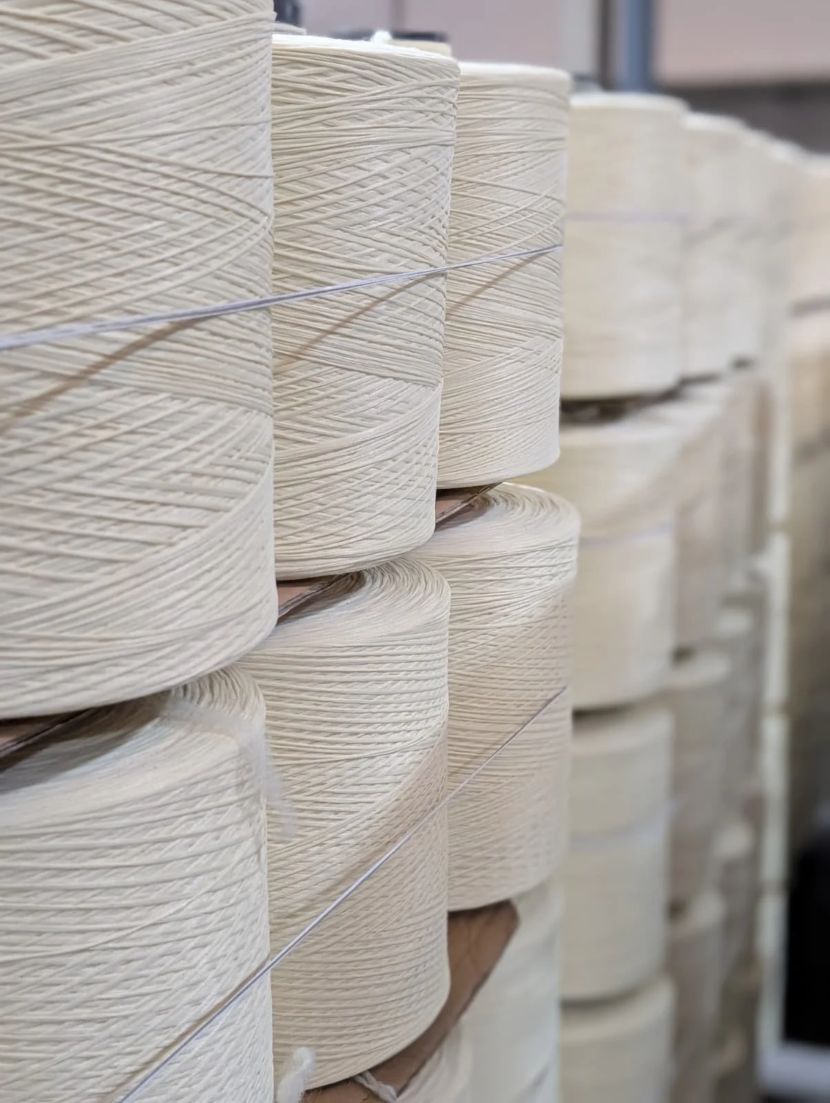 Multiple large spools of cream-colored thread stacked on shelves.