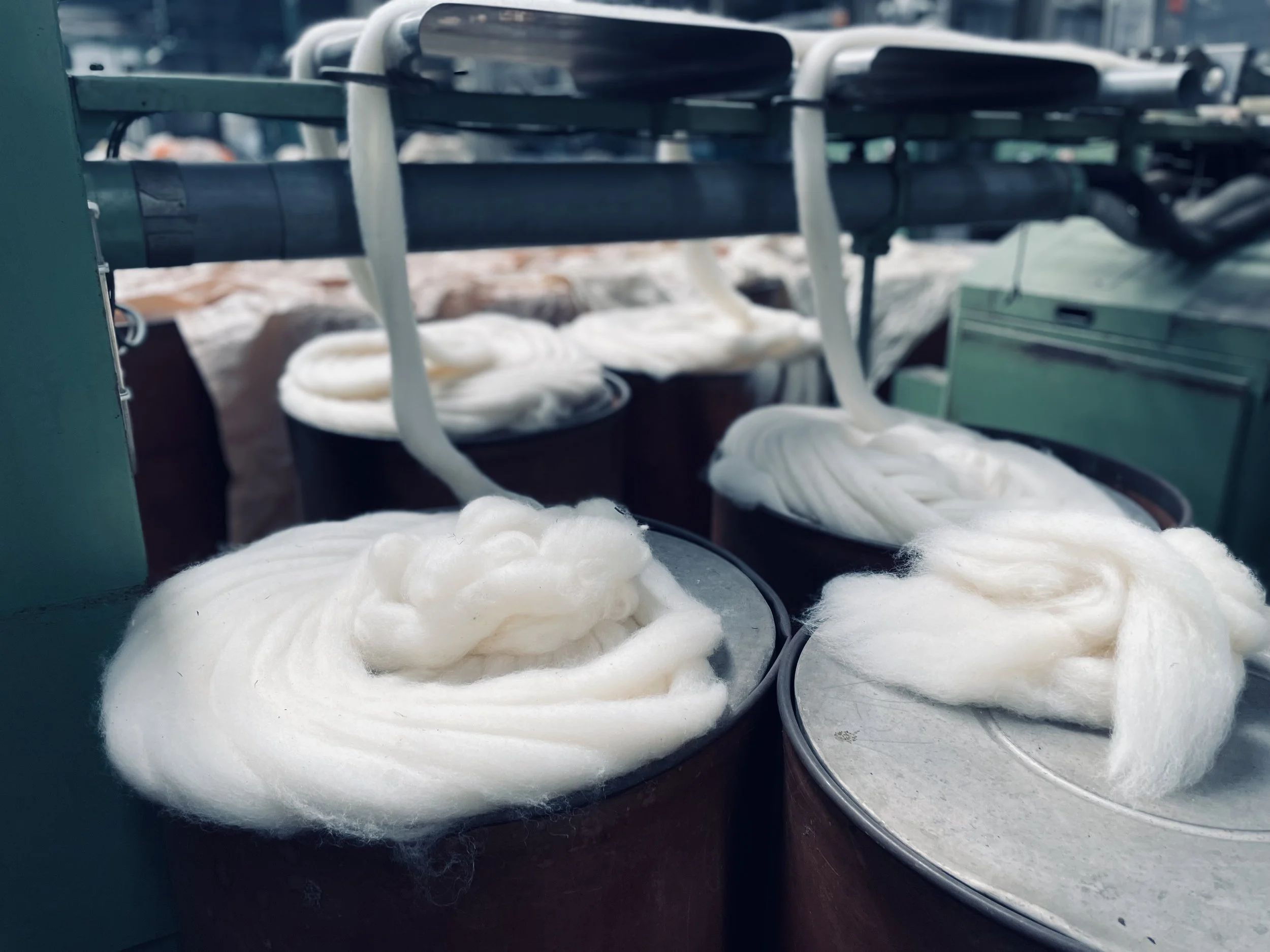 Silk or fiber being processed and stretched on metal or wooden drums in a factory or textile environment.