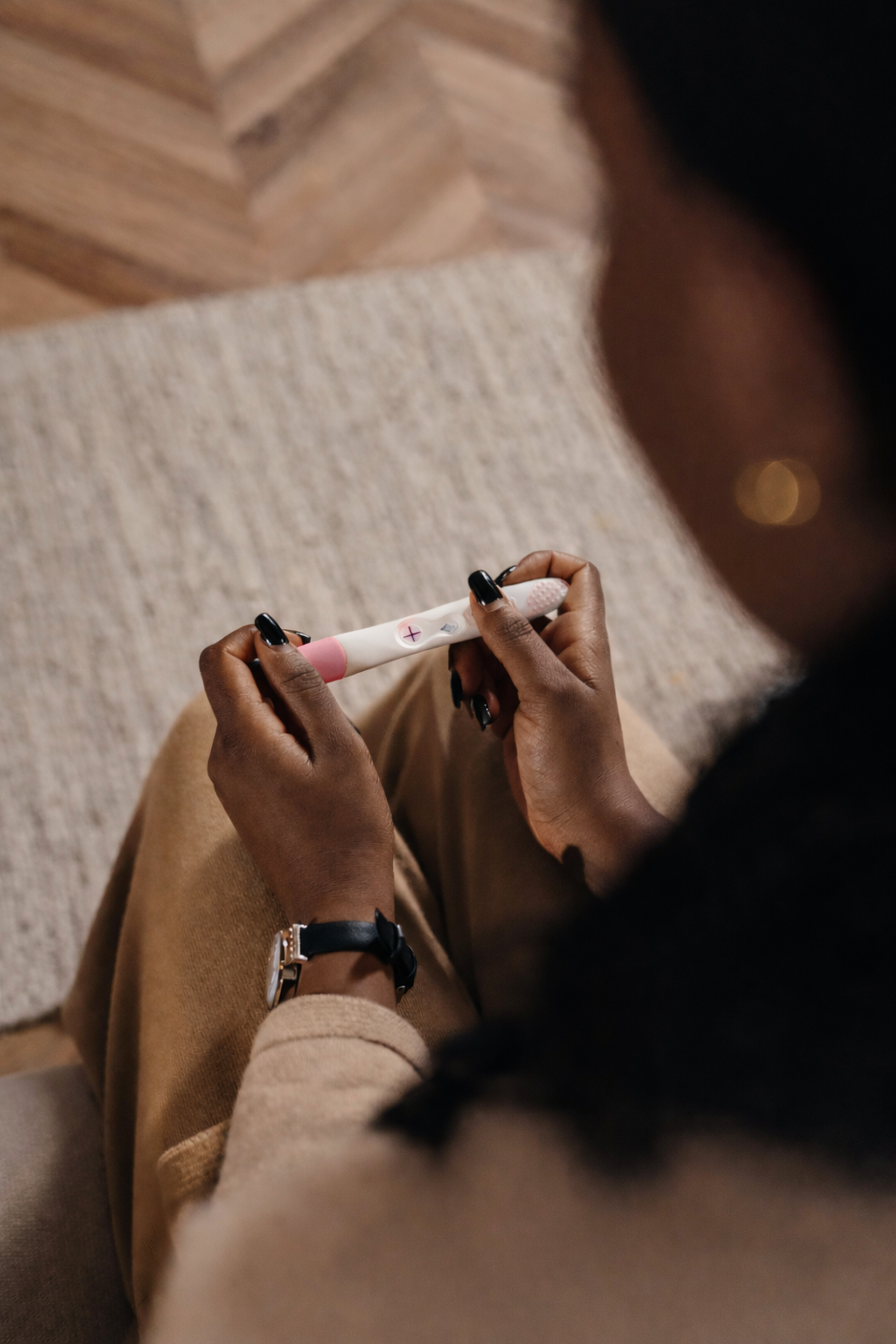 A person holding a positive pregnancy test with two pink lines.