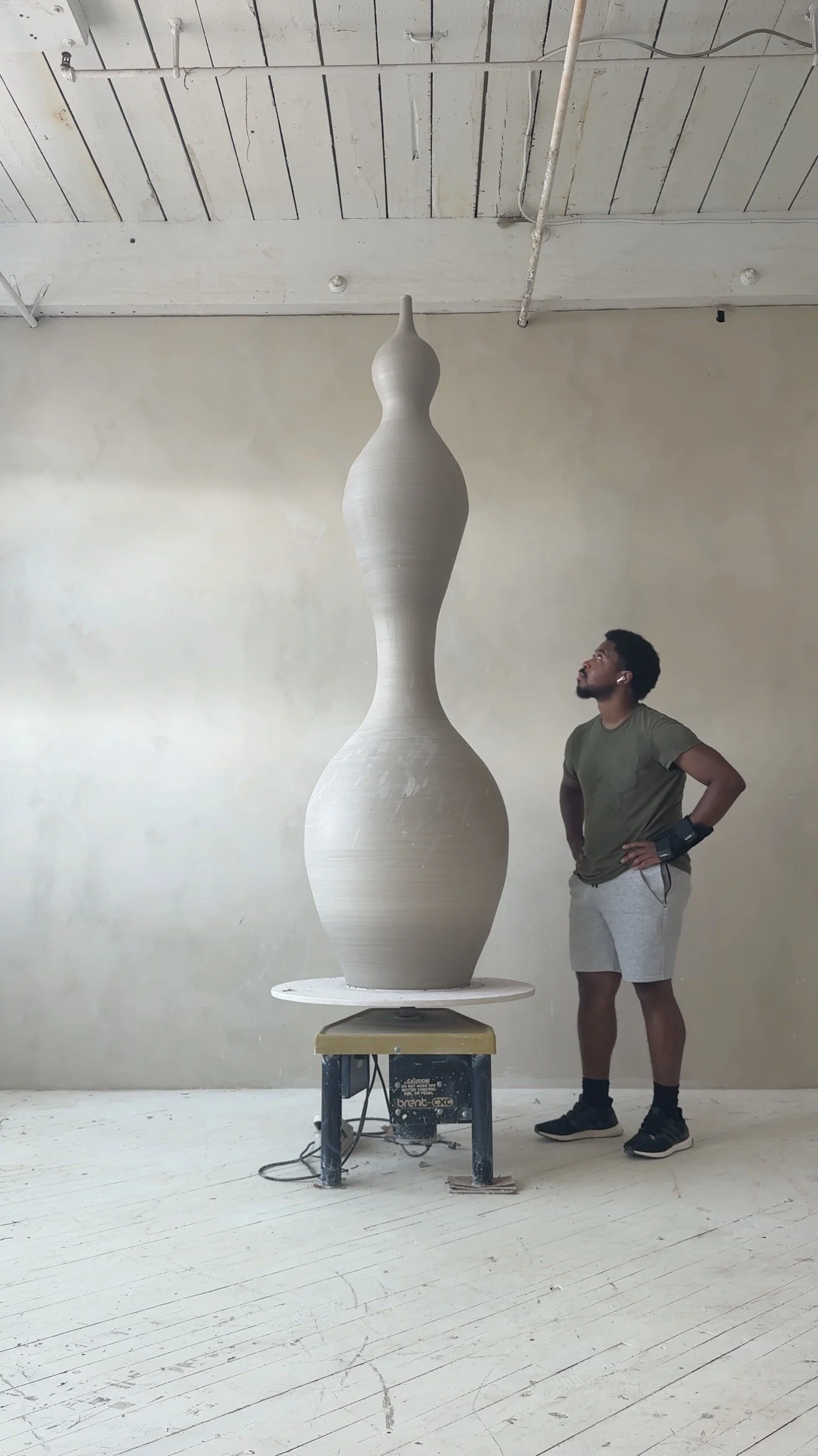 Khalil Jannah standing beside a monumental wheel-thrown clay vessel/monolith on a pottery wheel (Wetlock Method)