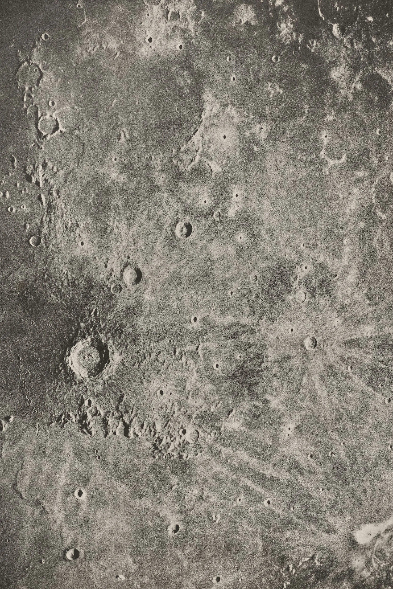 Photograph of the moon's surface showing numerous craters and rugged terrain.