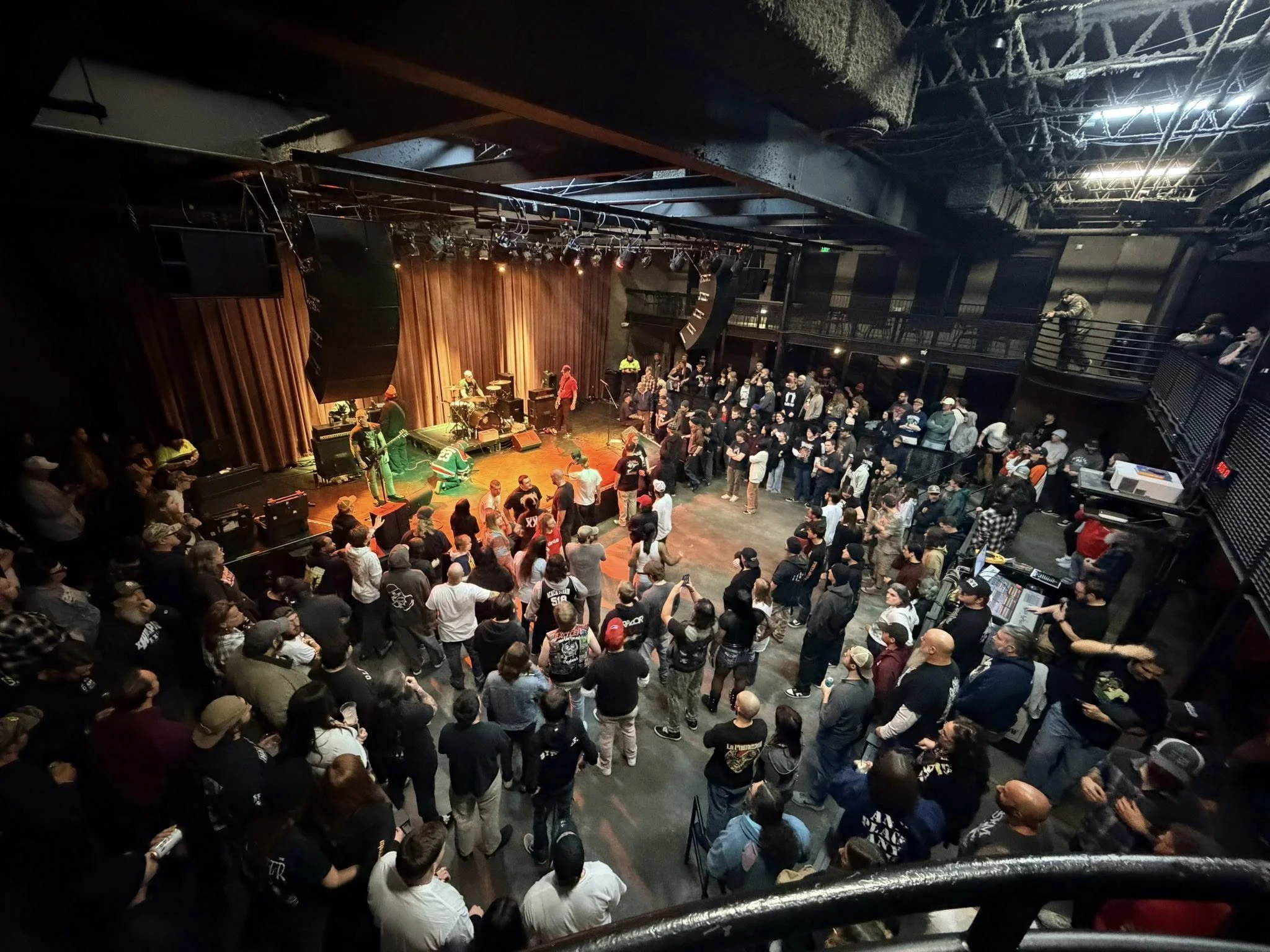 Crowd of people dancing in front of a live band performing on stage at a concert venue.