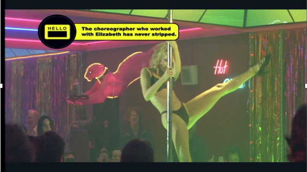 A still from the movie "Showgirls" with Elizabeth Berkley  in black underwear performing a pole dance in a nightclub with colorful neon lights and a sequined curtain background.