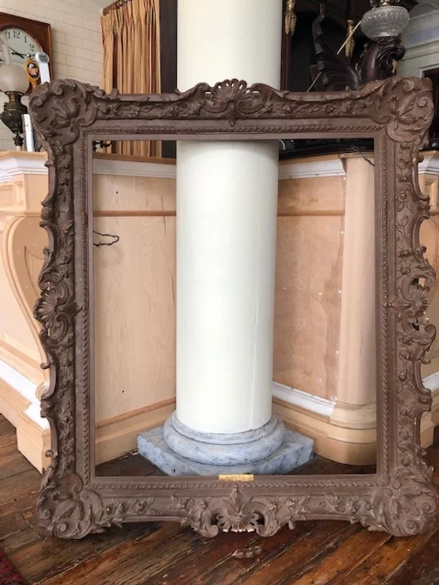 Decorative ornate wooden picture frame with a central white column inside it.