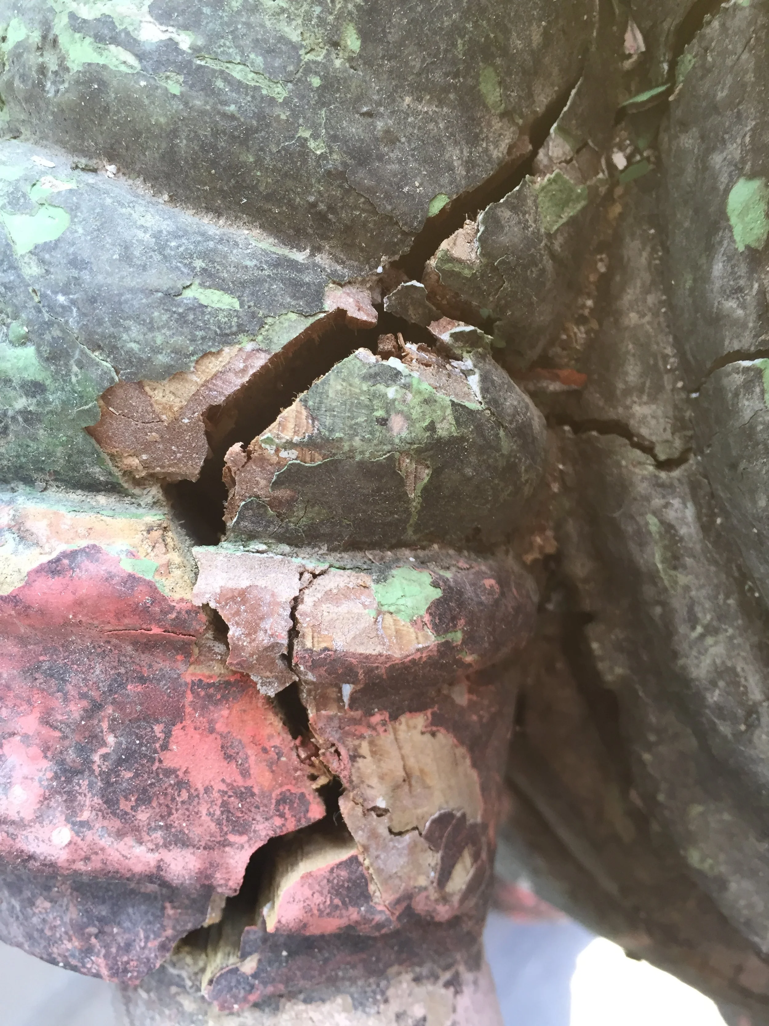 Close-up of cracked and peeling painted surface on an old, weathered brick wall.