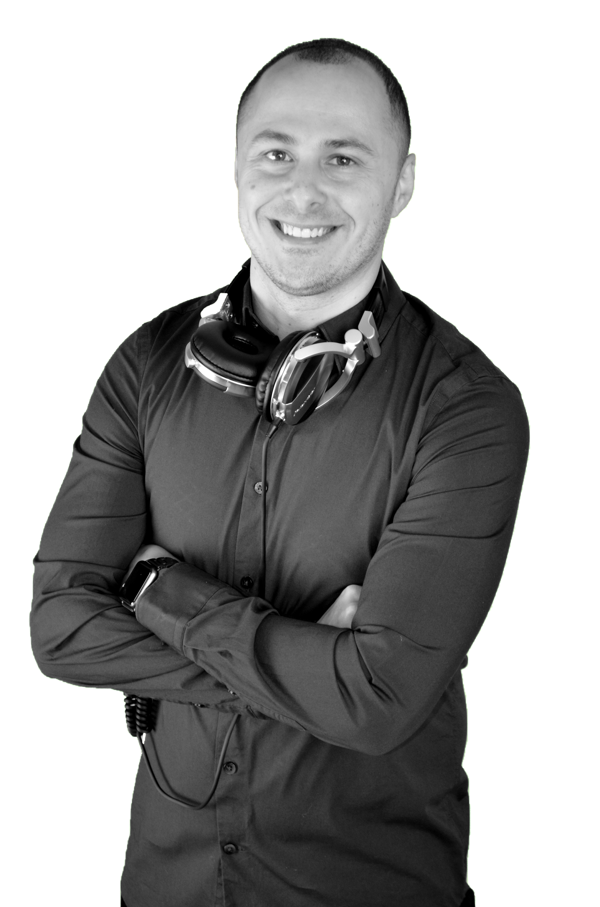 Black-and-white photo of DJ MV smiling, wearing a button-up shirt and a headset around his neck, with arms crossed.