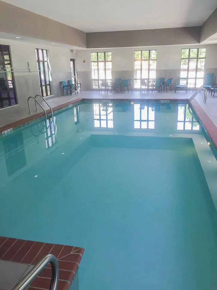 Commercial swimming pool with empty water and sunlight streaming through large windows at the far end of the room. Good Earth Pools, Oklahoma
