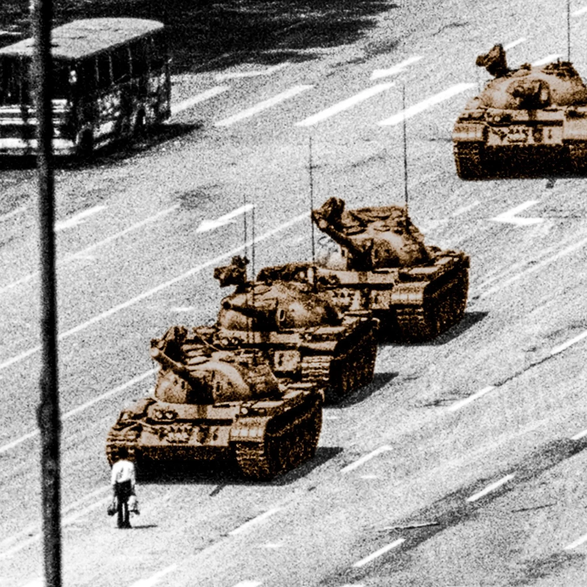 Three tanks and a person standing on a street with a bus or tram in the background. 1989 Tiananmen Square protests and massacre