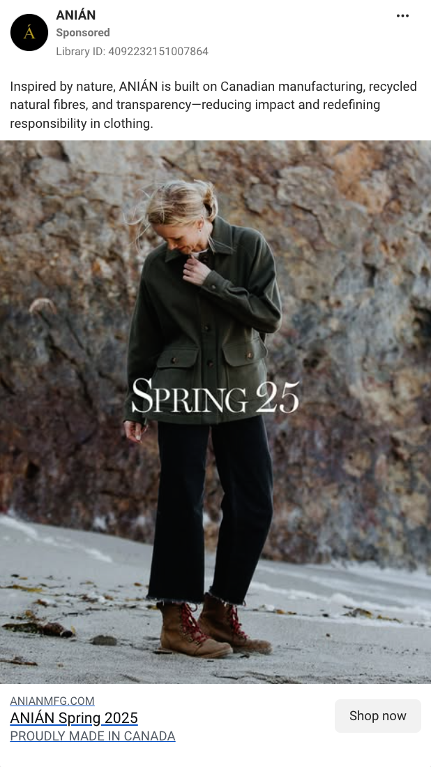 A woman standing outdoors on a beach with rocky cliffs in the background, wearing a green jacket, black pants, and brown boots.