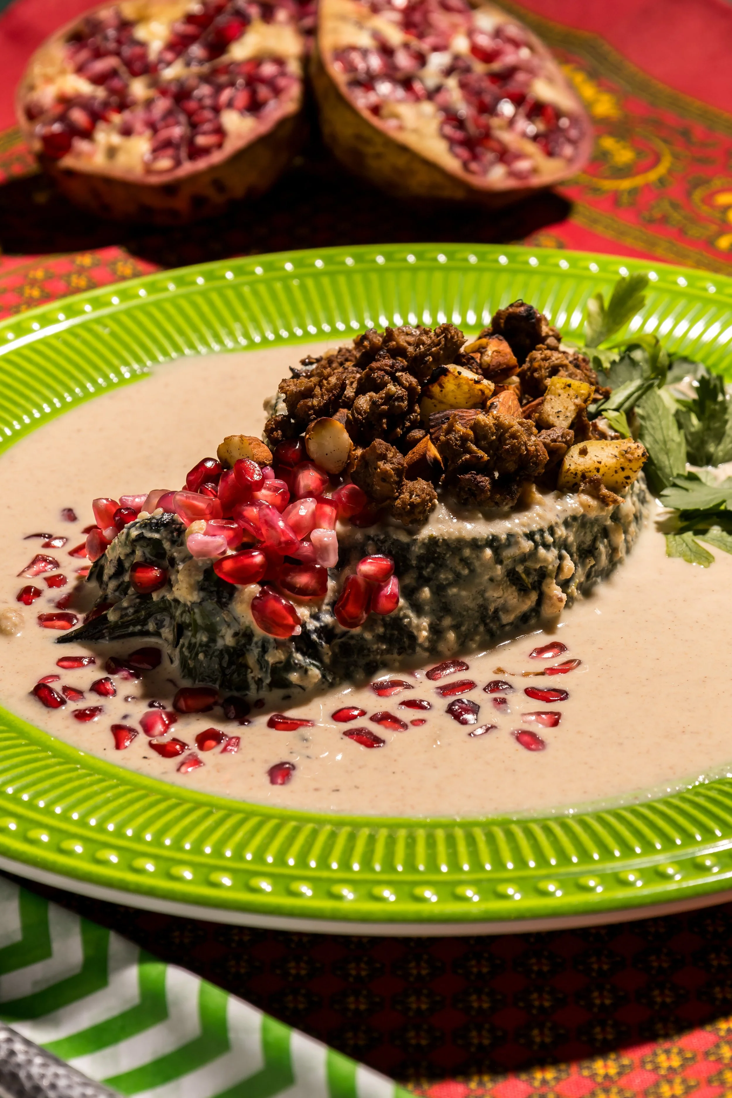 Pescado en salsa blanca con granada y carne seca, servido en plato verde, en fondo con frutas