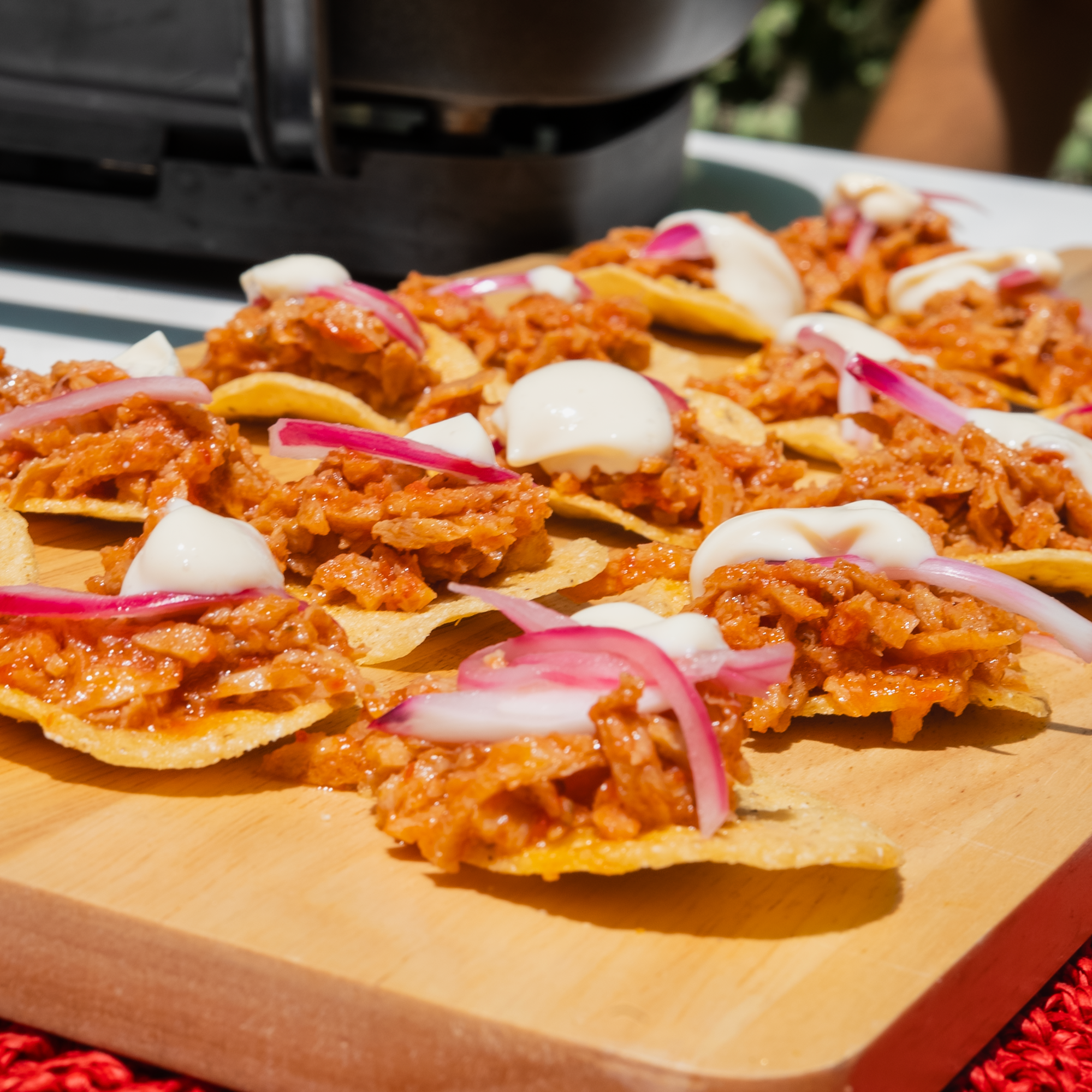 Tostadas de tinga de pollo vegano con crema y cebolla en una tabla de madera.