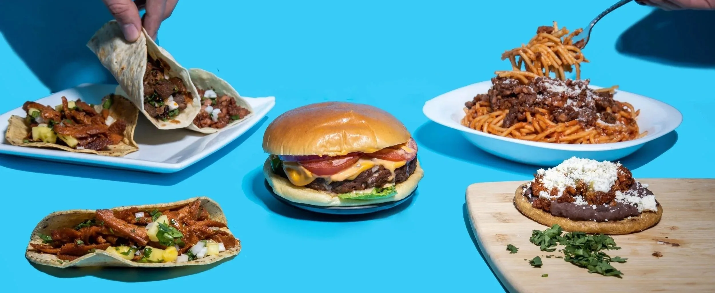 Variedad de comida rápida, incluyendo tacos, hamburguesa, spaghetti, todo siendo vegano.