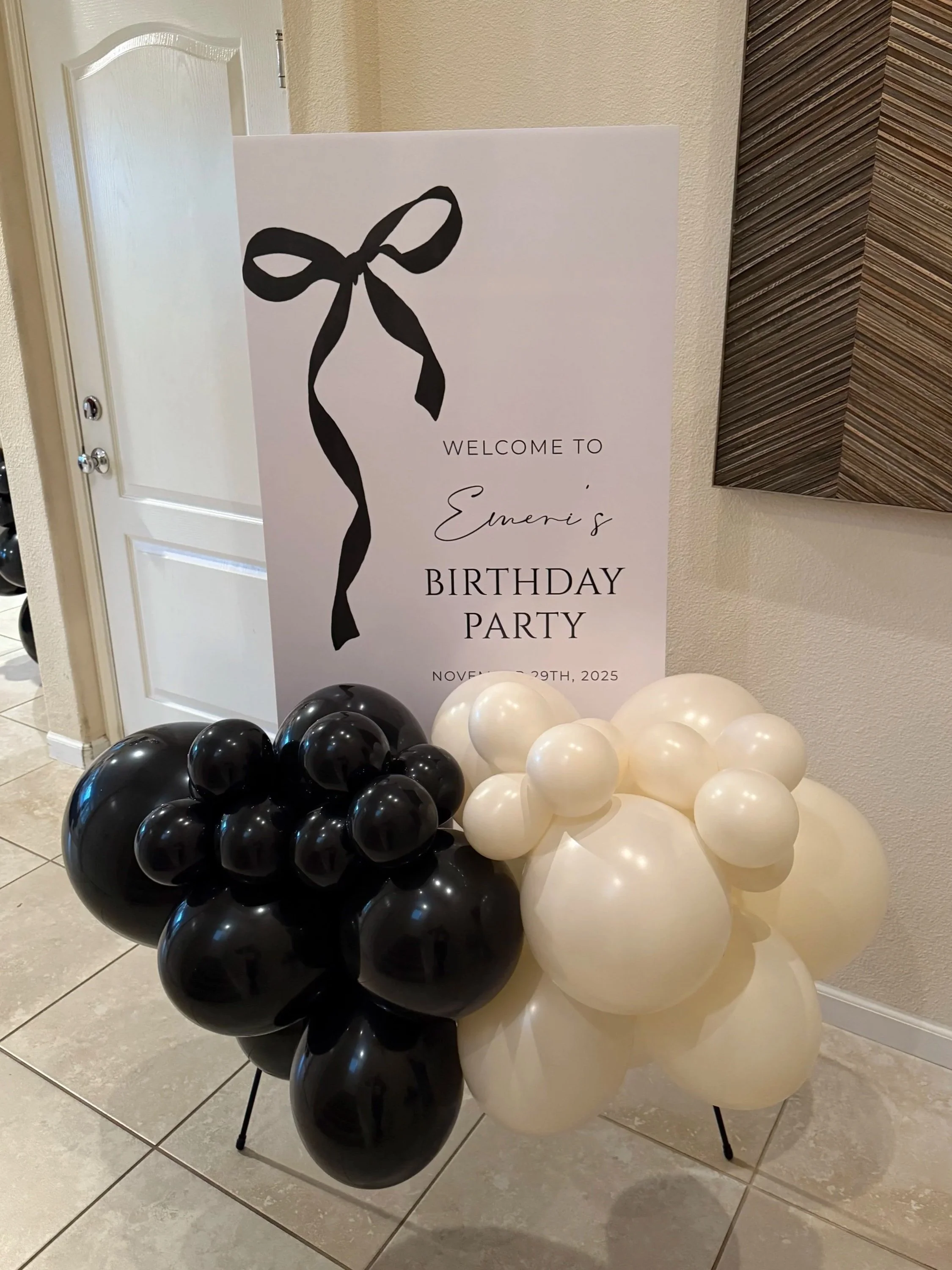 Balloon display with black and white balloons and a sign that says 'Welcome to Emani's Birthday Party, November 29th, 2025'.