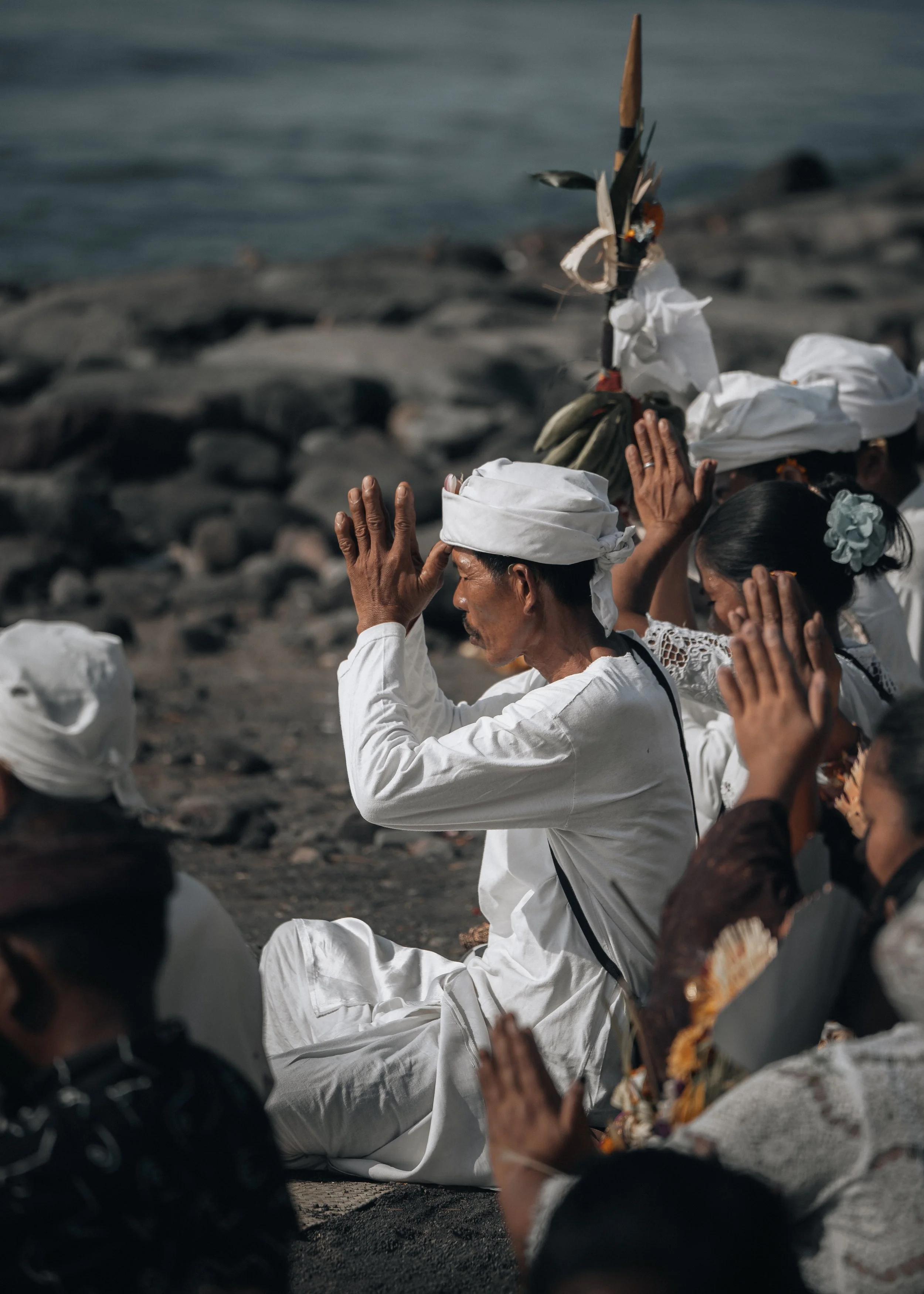 Des personnes en tenue traditionnelle indonésienne portant des offrandes lors d'une cérémonie religieuse sur la plage