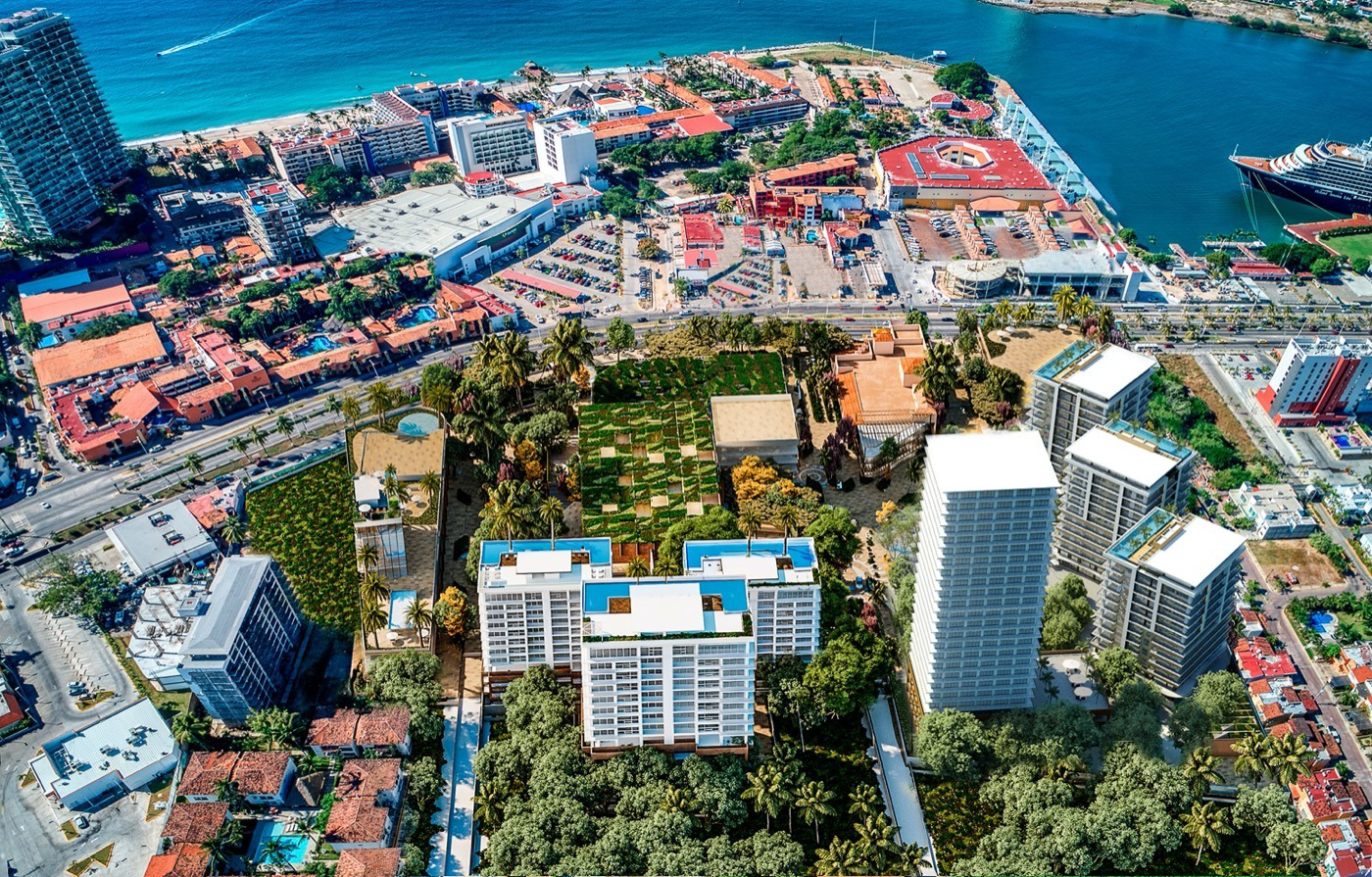 Vista aérea de una ciudad costera con edificios altos, una marina con cruceros, áreas verdes y calles concurridas.