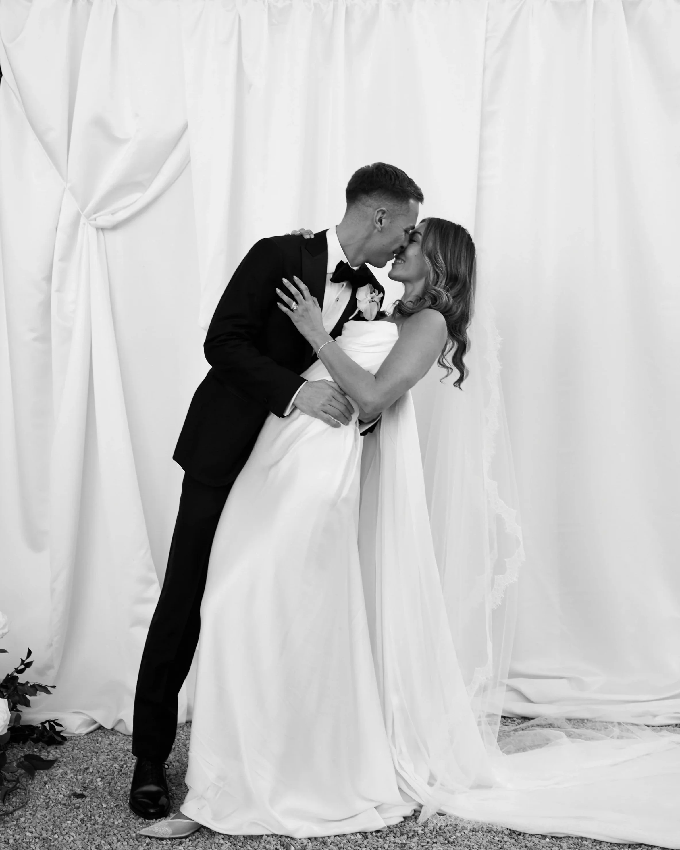 Black and White photo of Bride and Groom Kissing. Editorial style image photographed by a fashion photographer. 