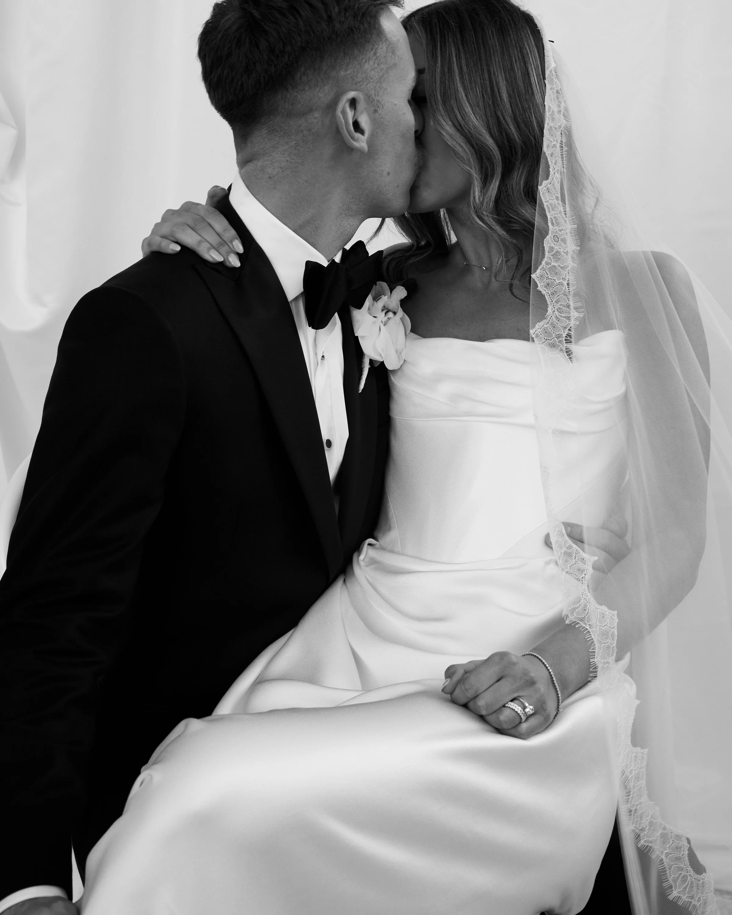 Black and White photo of Bride and Groom Kissing. Editorial style image photographed by a fashion photographer. 