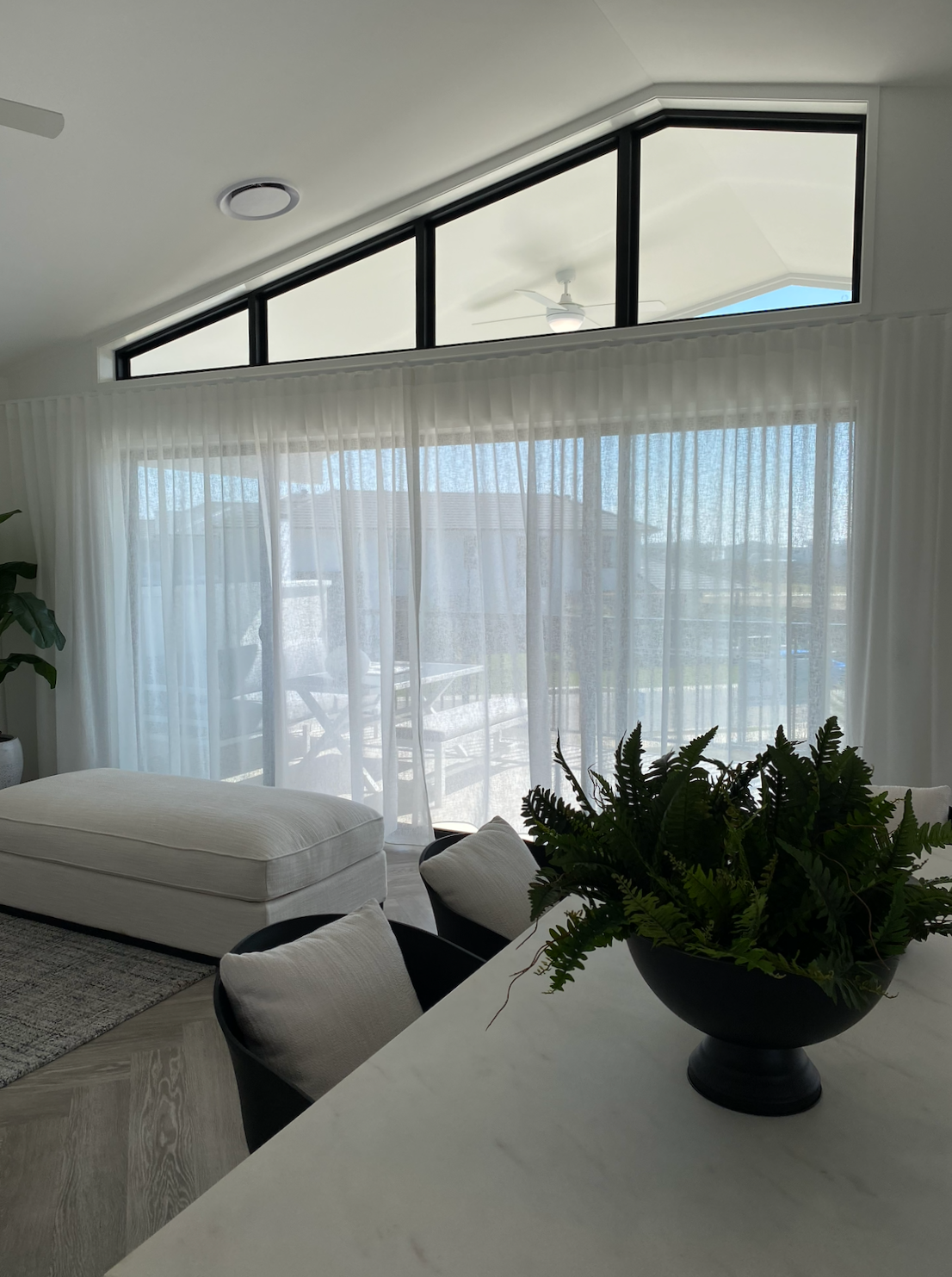 Living room with large window covered by sheer white curtains.