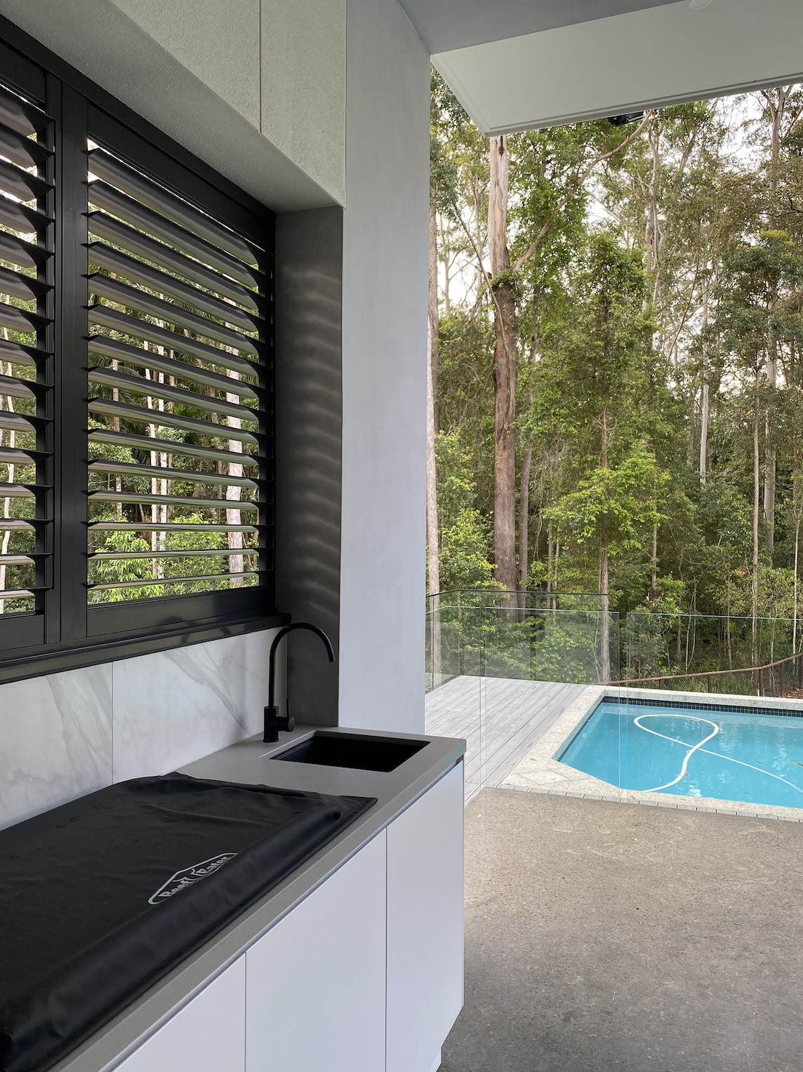 A modern outdoor pool area with black shutters.