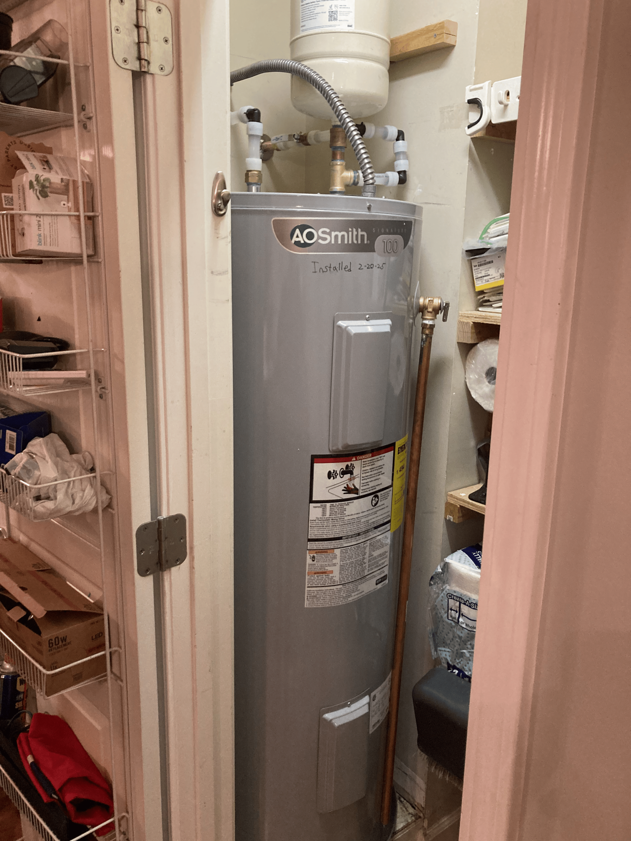 Plumber installing AO Smith water heater in residential utility closet