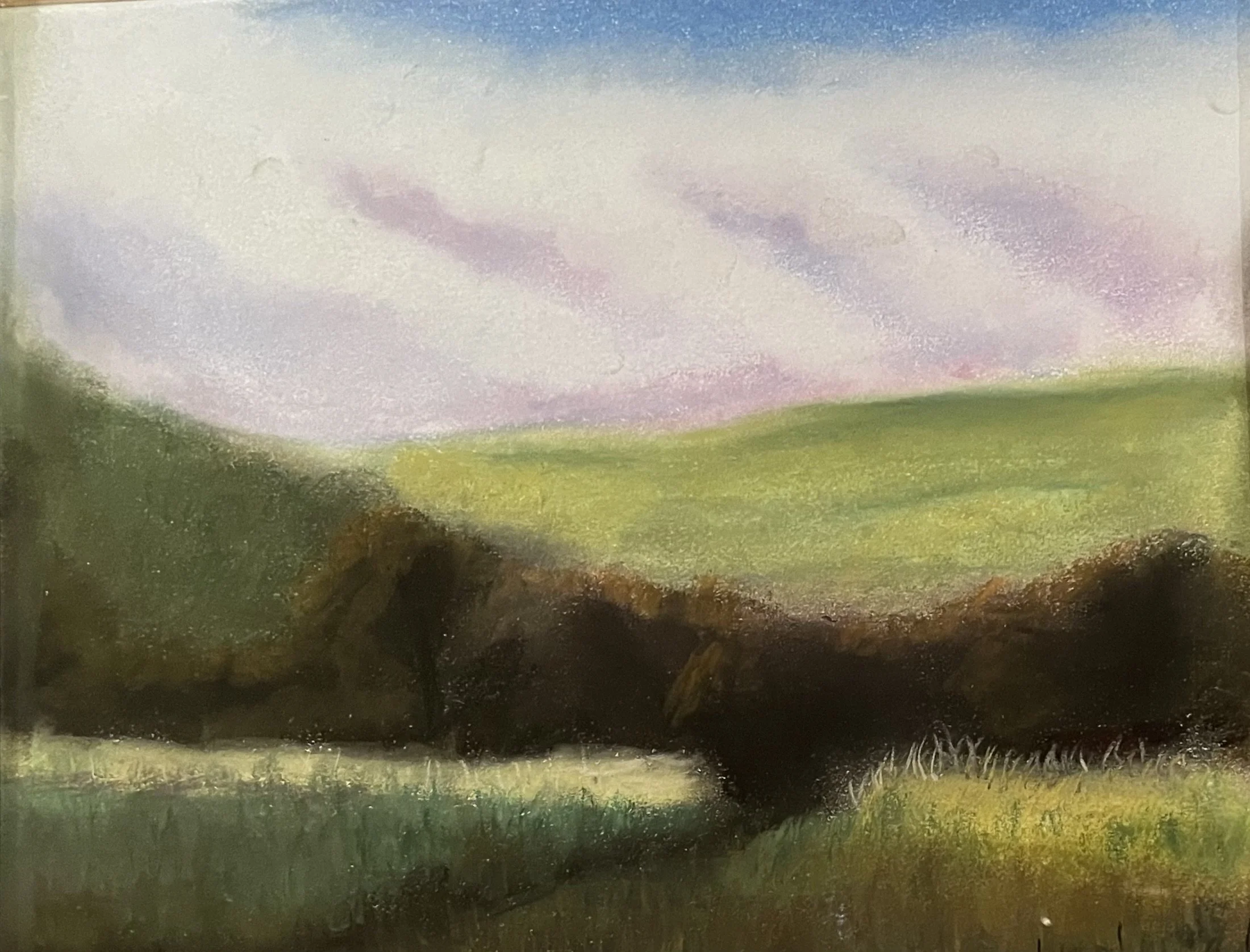 A pastoral landscape painting featuring rolling green hills, dark trees in the foreground, and a pastel-colored sky with pink and purple clouds.