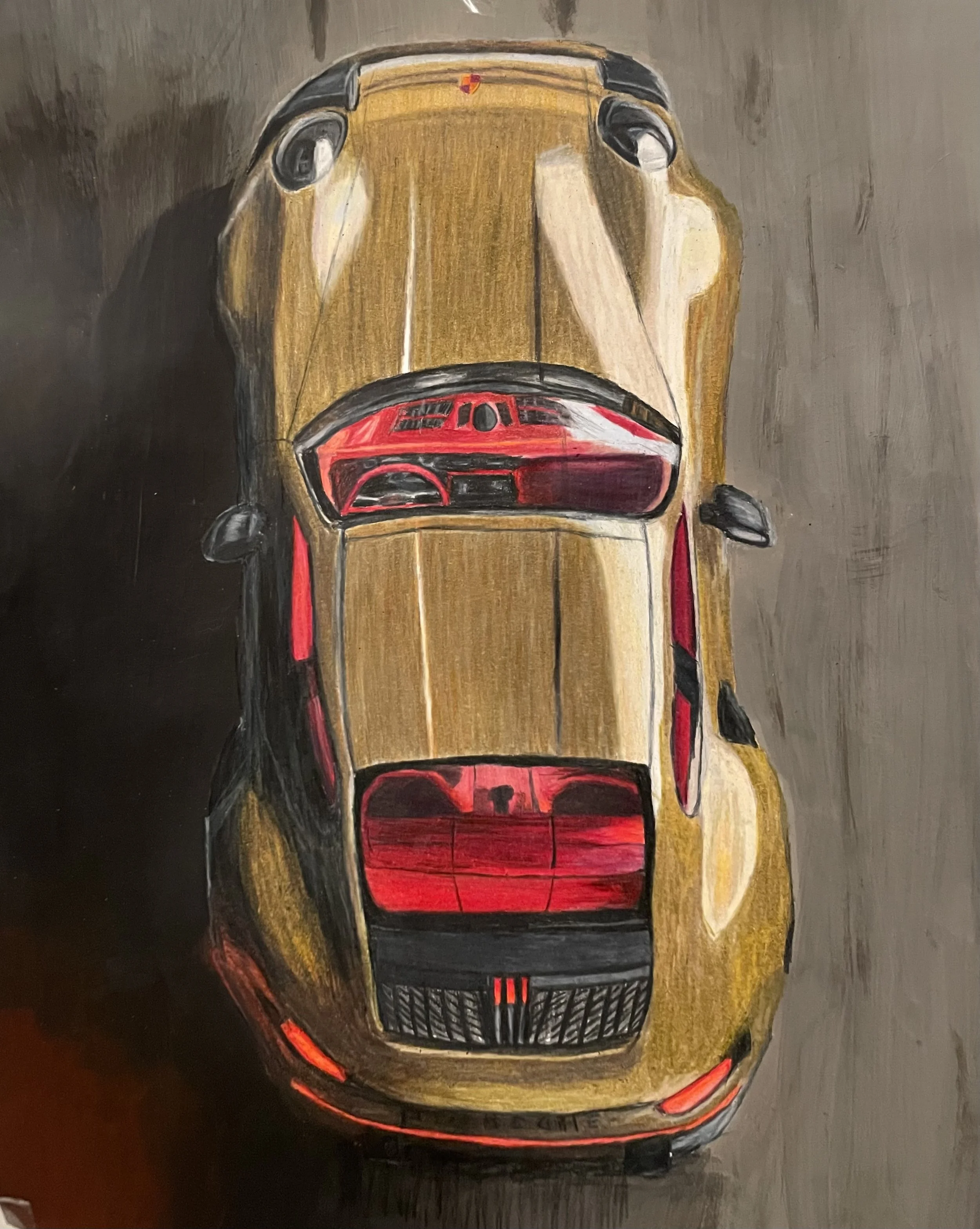 Top-down view of a modern sports car painted with a gold and black exterior, featuring red interior accents visible through the windshield and rear window.