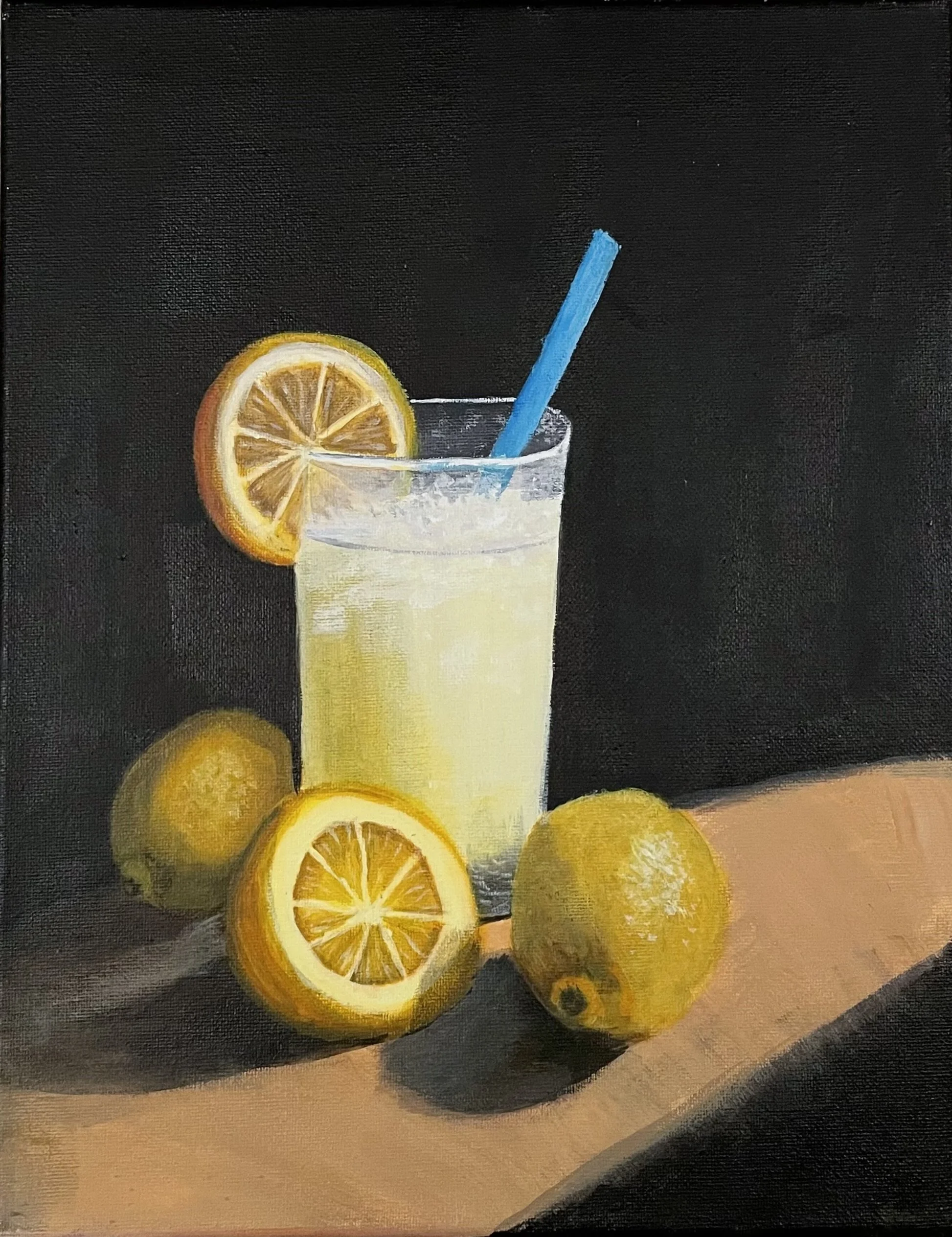 A glass of lemonade with a blue straw and a lemon slice, surrounded by whole and sliced lemons, on a wooden surface against a dark background.