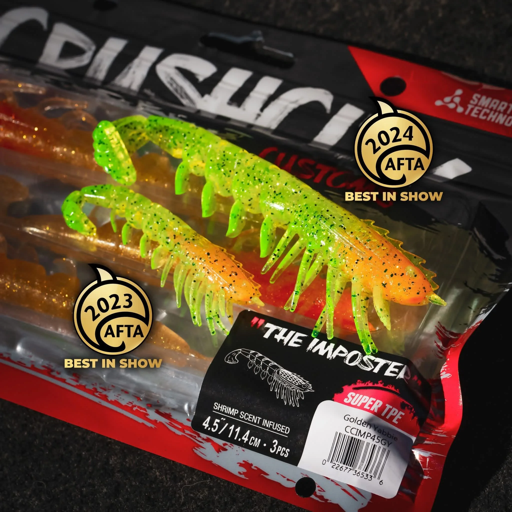 Green and orange soft plastic fishing lures shaped like crustaceans with black glitter specks on a fishing lure packaging box.