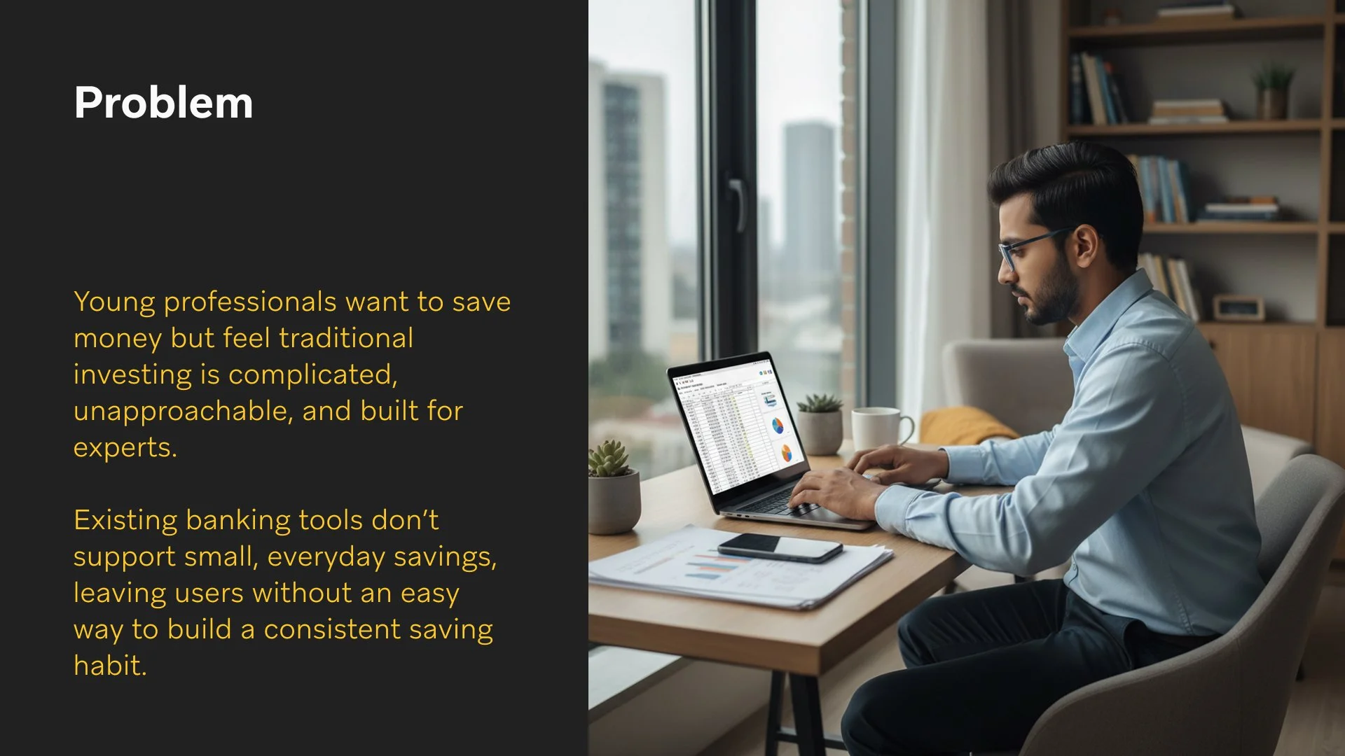 Man working on a laptop at a desk near a large window with a city view, with a phone, papers, and plants on the desk.