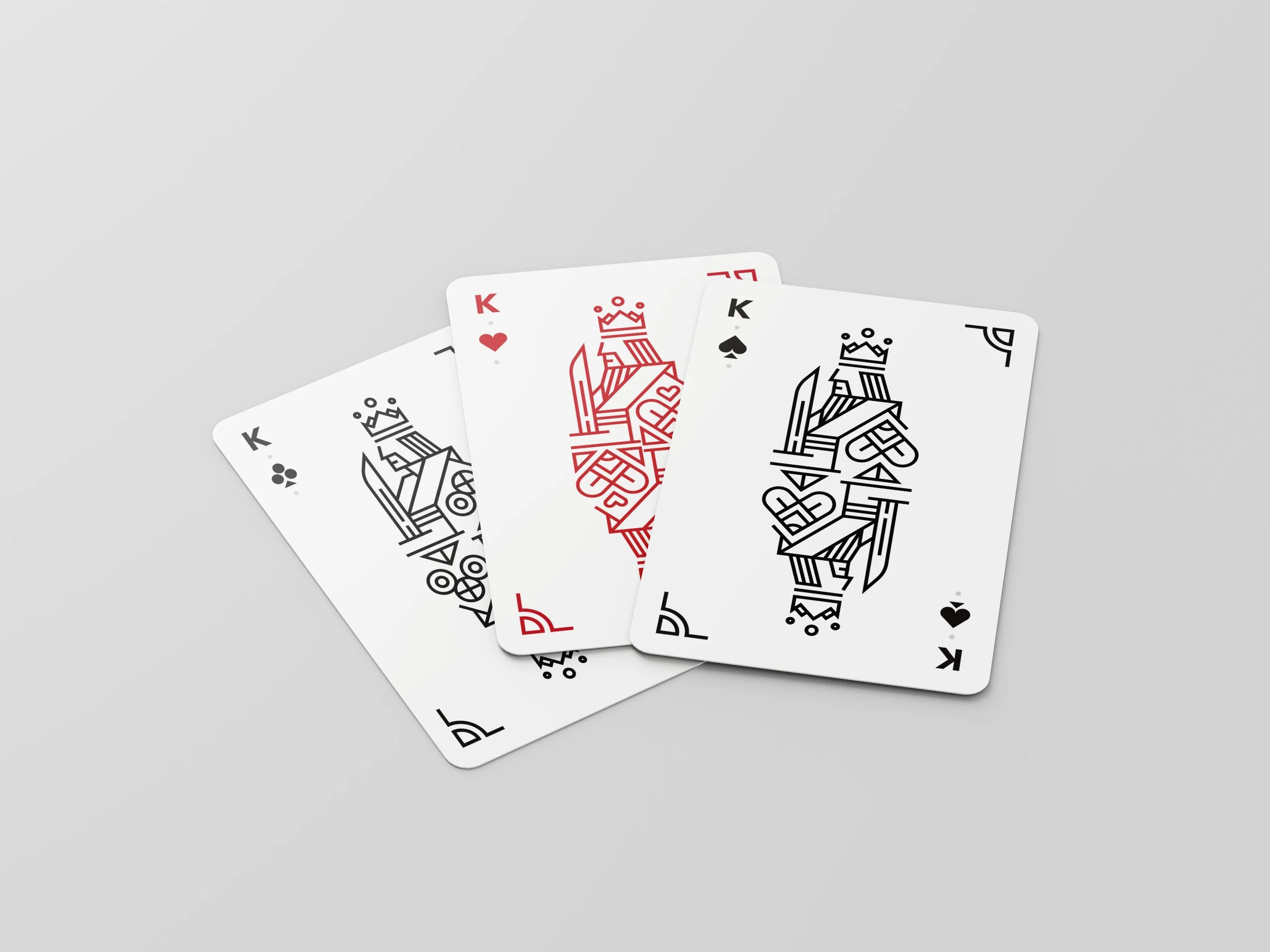 Three playing cards, all Kings, with stylized geometric designs of crowns and castles on the face. The cards are the King of Clubs, King of Hearts, and King of Spades.