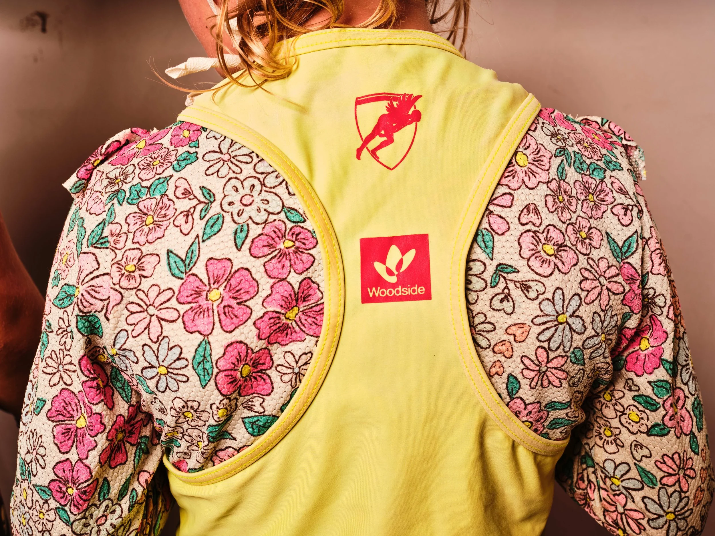 A child in a Surf Life Saving WA vest displaying fossil fuel polluter Woodside's logo