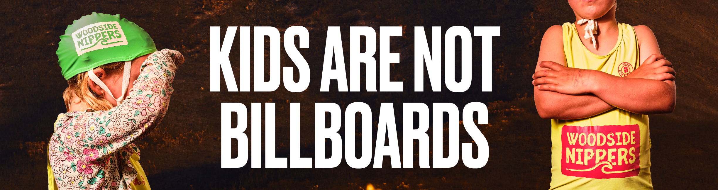 Children in Surf Life Saving WA vests and caps displaying fossil fuel polluter Woodside's logo